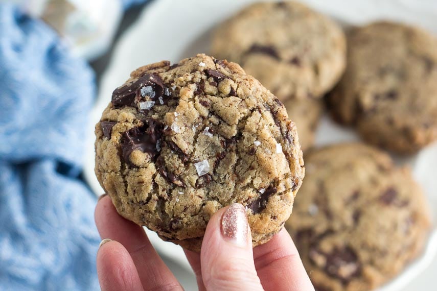 closeup of low FODMAP vegan chocolate chunk cookie sprinkled with salt; held in hand